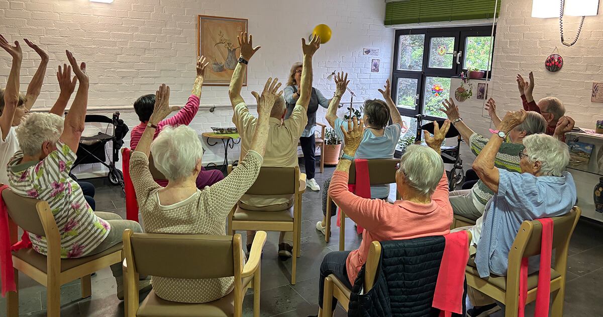 Seniorengruppe bei Gymnastik mit Ball im Gemeinschaftsraum